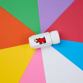 Blackwing Volume 292 One-Step Sharpener in white with Keith Haring's "Dog" illustration in red - seen on a multi-color background